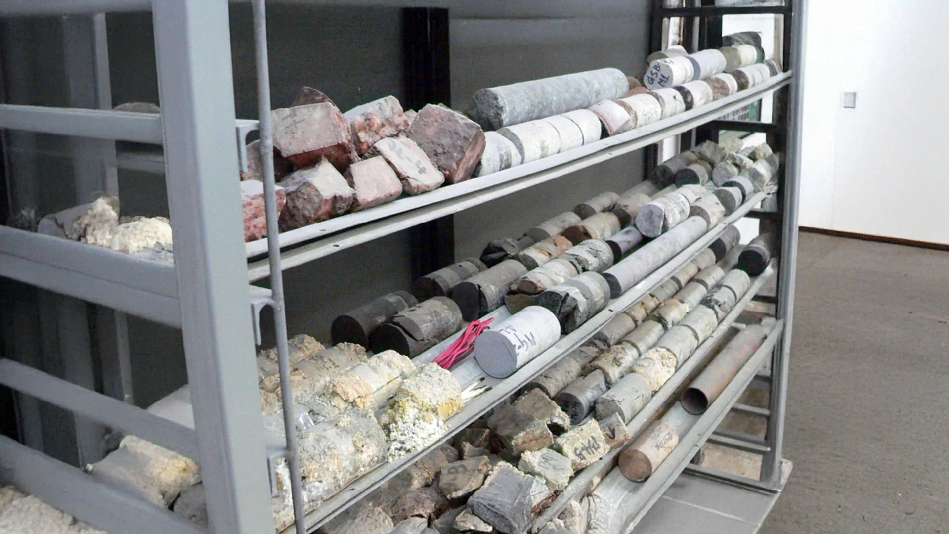 Muestras de núcleos de roca y minerales en estantería, destinadas a caracterización geológica bajo normativa ambiental